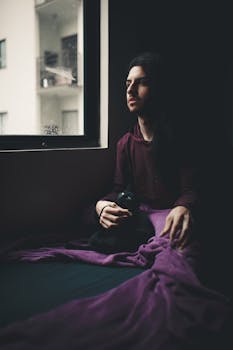 窗户旁坐着一位体贴的人，一只黑猫相伴，笼罩在舒适的氛围中