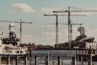 Contemporary industrial cargo port with tall weightlifting cranes and moored modern vessels near pier on clear weather