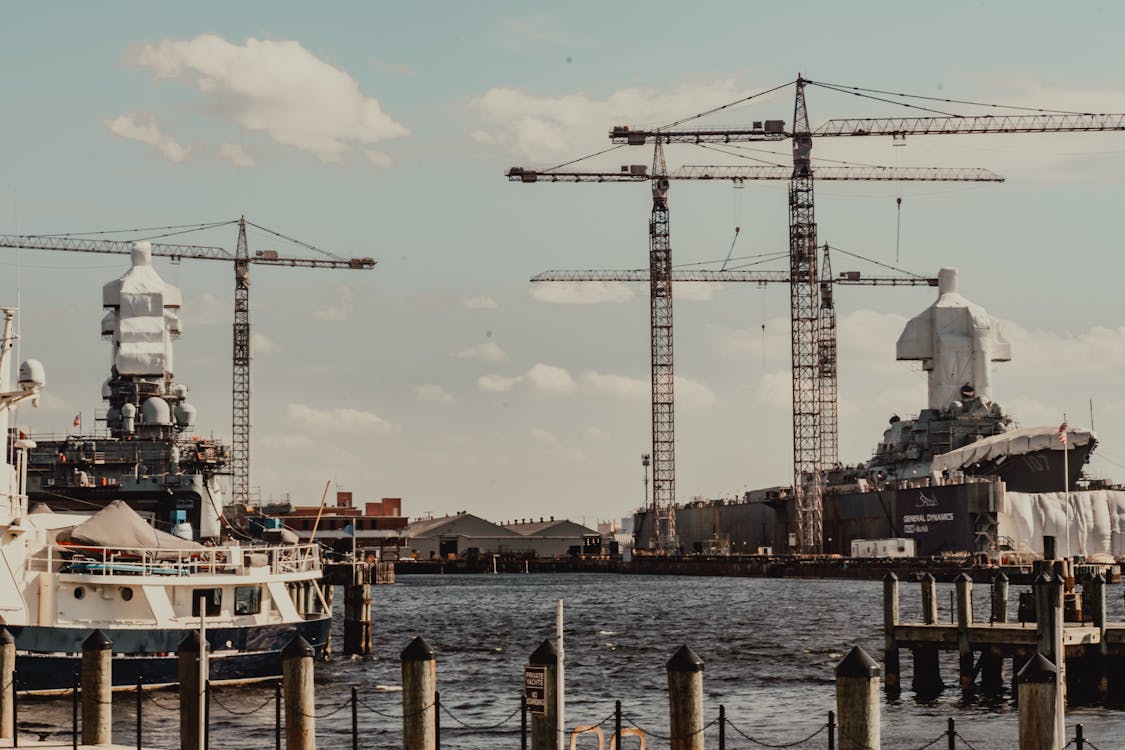 Contemporary industrial cargo port with tall weightlifting cranes and moored modern vessels near pier on clear weather