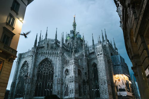 Free From below of Milan Cathedral of Nativity of Saint Mary with facade advertising on one side under cloudy sky on quiet evening Stock Photo