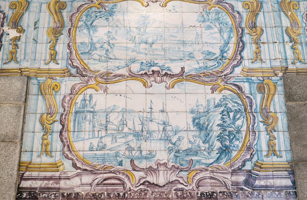 Amazing Azulejo tin glazed ceramic tilework depicting pastoral scene and ship in port on wall of building in Porto city in Portugal
