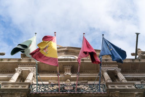 Flags waving on old ornate city building on fine day