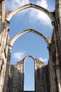 From below of ancient pointed stone arches of Convent of Lady of Mount Carmel in Portugal in sunlight under clear blue sky