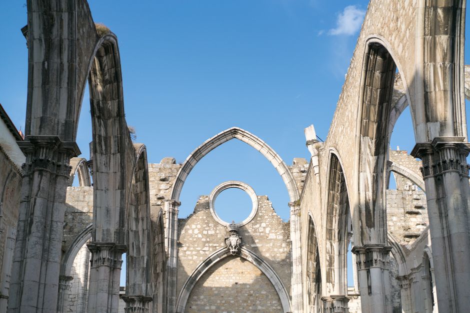 Aged pointed arches of ruined part of Convent of Lady of Mount Carmel in Lisbon in bright sunlight under clear blue summer sky — Terramoto, Portugal.