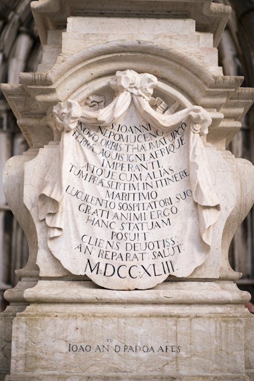 Elegant plaque with Latin inscription on pedestal of marble statue of Saint John of Nepomuk in Lisbon