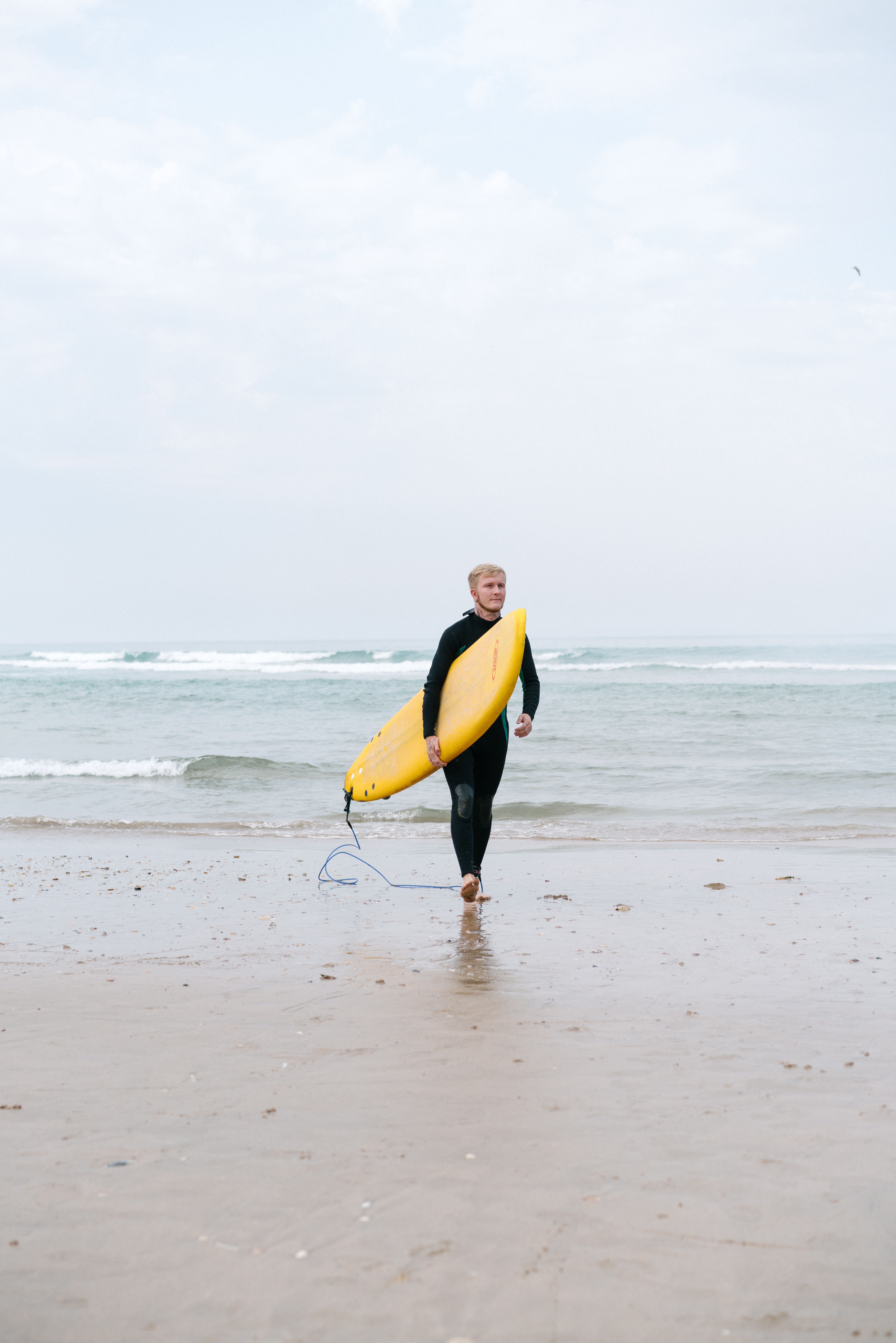 Male surfing instructor with surfboard on ocean shore · Free Stock Photo