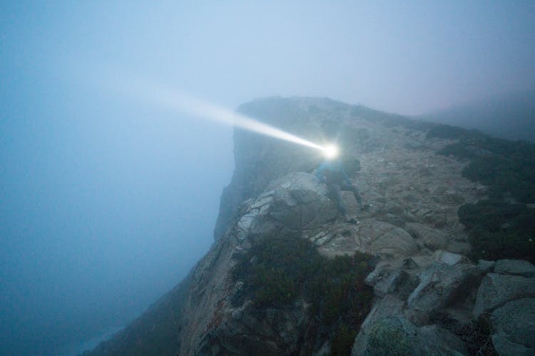 Person With Flashlight On Cliff Top At Night