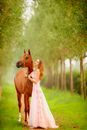 Gorgeous woman near brown horse in garden