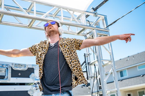 Trendy young man in headphones dancing on stage during music festival