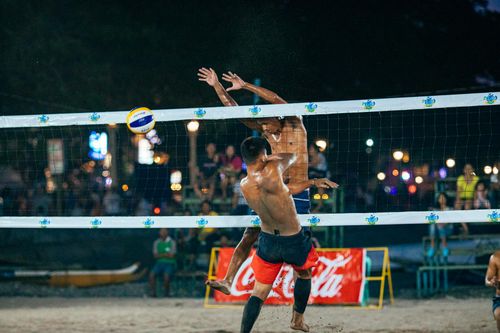 Free Energetic beach volleyball match under night lights with athletic players. Stock Photo