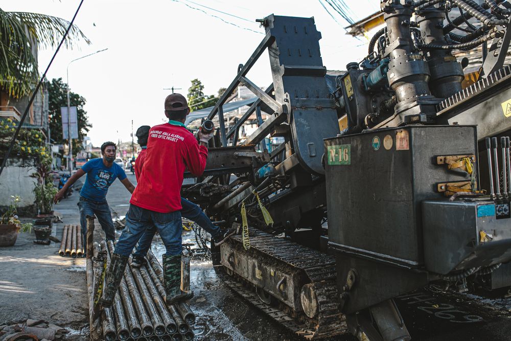 Crew running a horizontal boring rig to drive a new line beneath a street