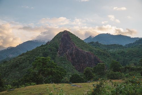 Free Beautiful mountain landscape with lush greenery and dramatic clouds at sunset. Stock Photo