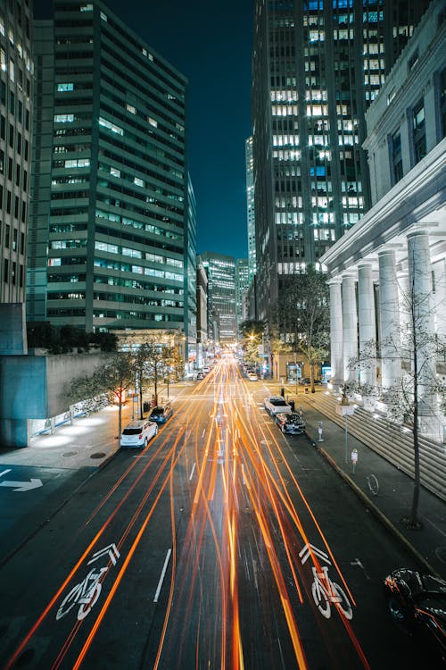 Cars on Road Between High Rise Buildings during Night Time