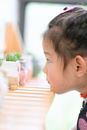 一个可爱的亚洲小女孩坐在木桌旁，看着小装饰植物的侧视图