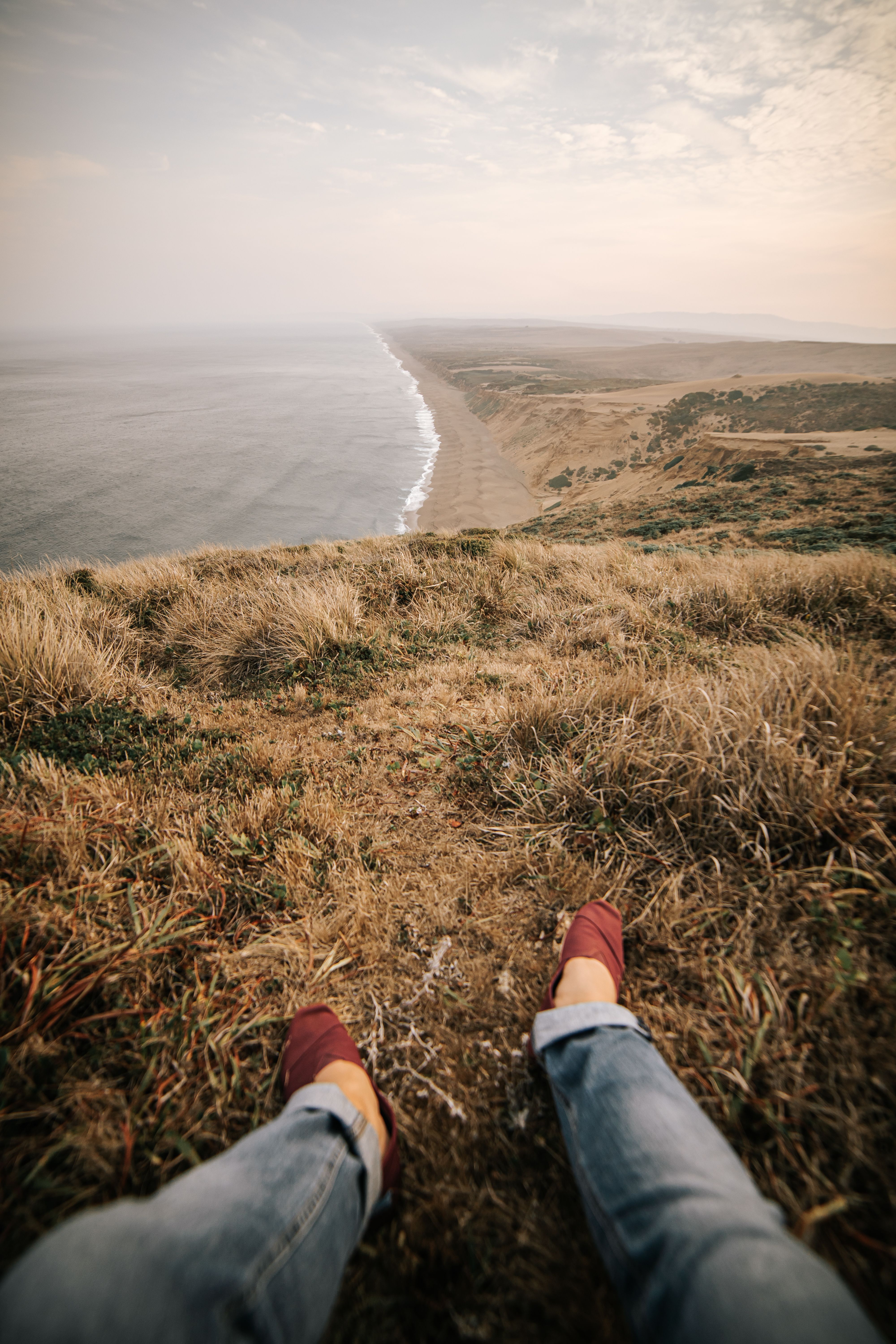 Runner pausing on coastal grass overlooking the Point Reyes shoreline and Pacific Ocean
