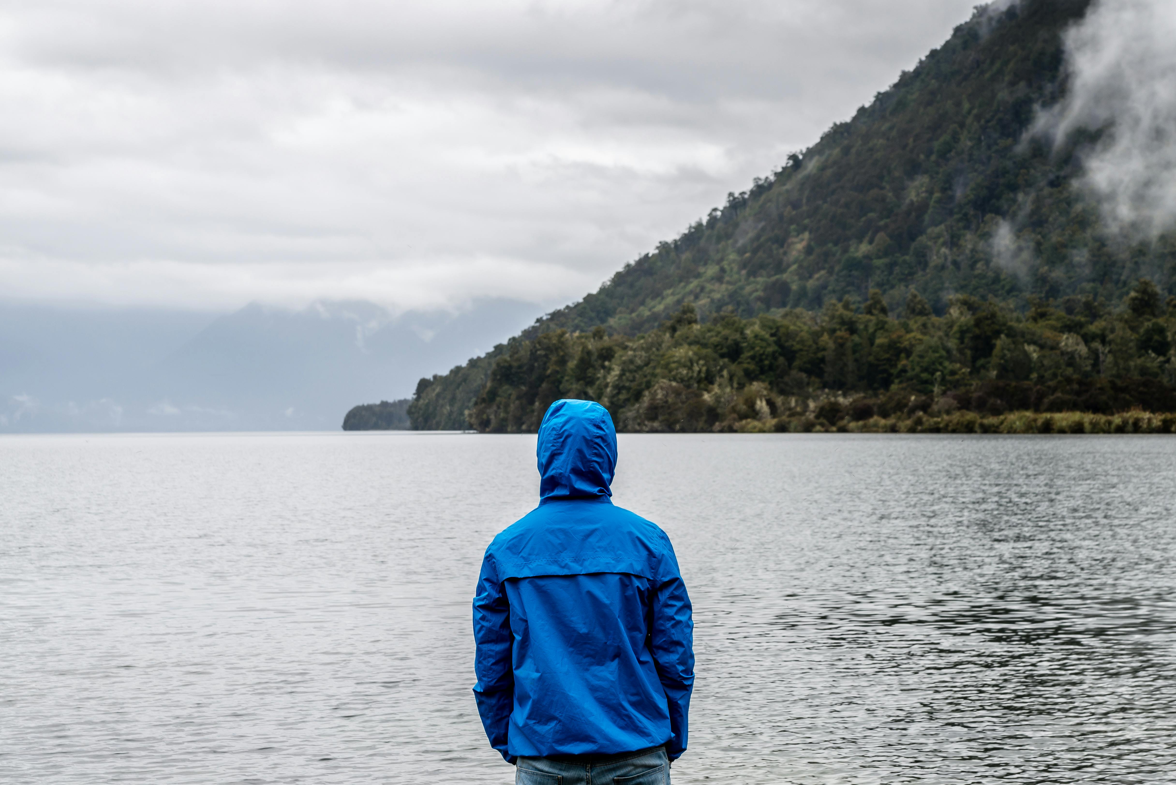 person wearing blue hoodie near body of water