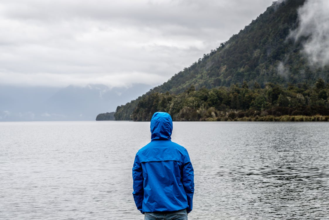 Free Person Wearing Blue Hoodie Near Body of Water Stock Photo