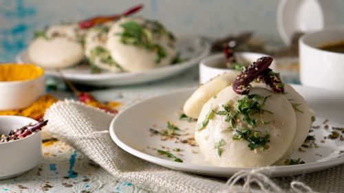 Free Plate of Indian Idli rice cakes served on table with herbs and sun dried chili pepper Stock Photo