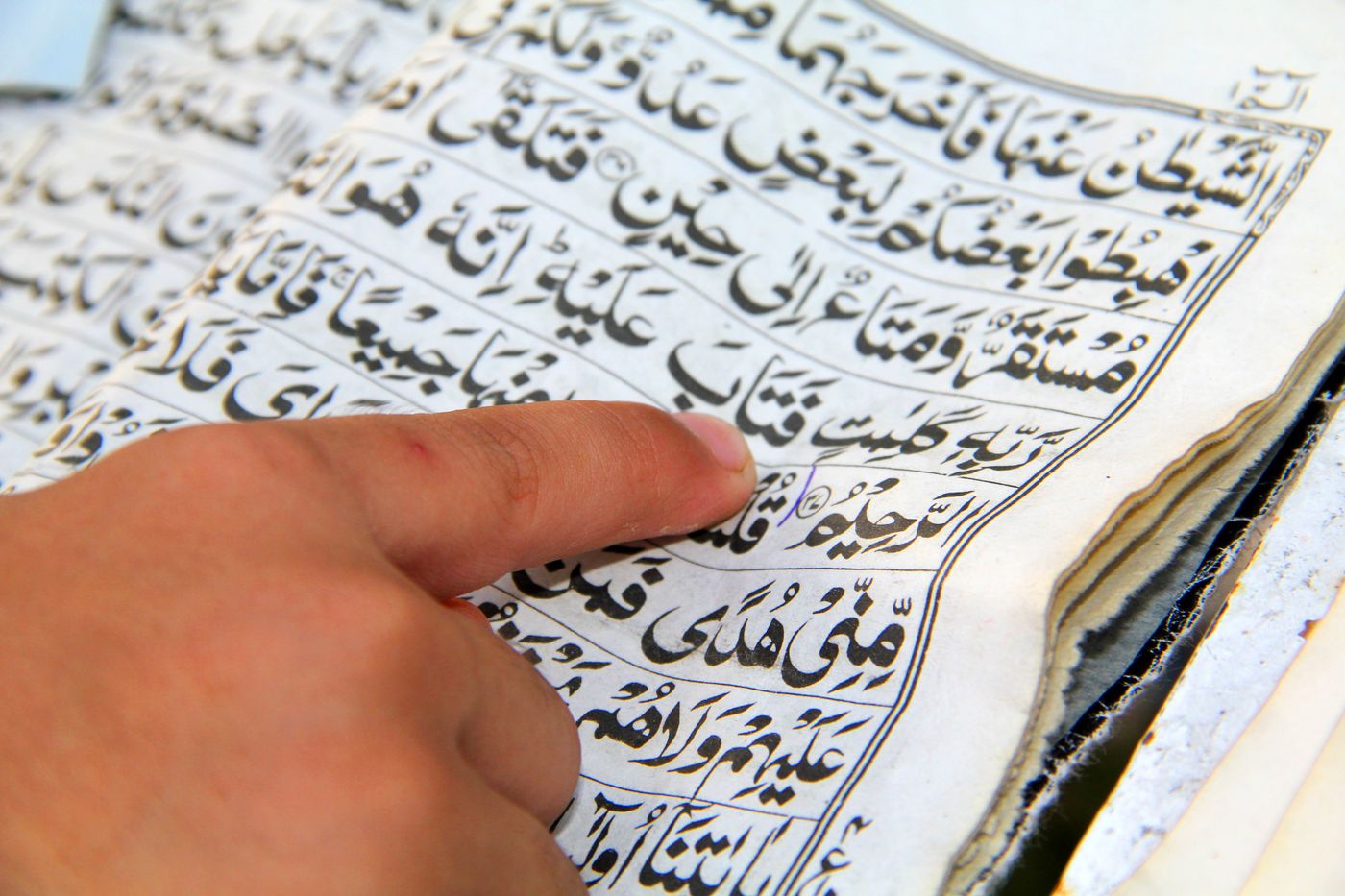 Un doigt suit les mots d’un passage du Coran