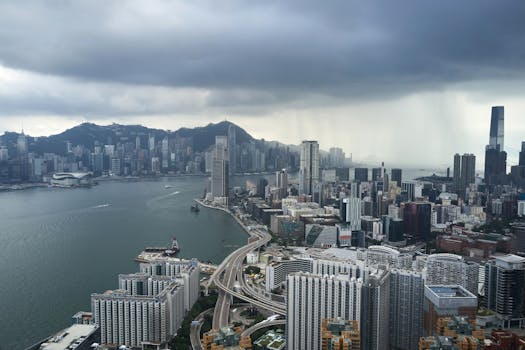 A breathtaking aerial view of Hong Kong's Kowloon skyline under dark, stormy clouds.