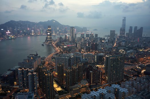 Stunning aerial shot of Kowloon, Hong Kong cityscape with skyscrapers and harbor at dusk.