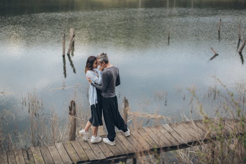 High angle side view of tranquil couple embracing each other while spending time together near pond