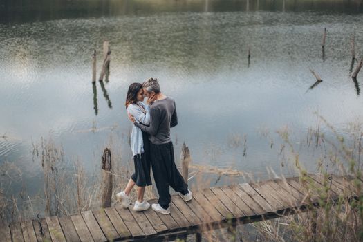 一对宁静的夫妇在池塘边共度时光时，从高角度侧视拍摄到他们互相拥抱的画面