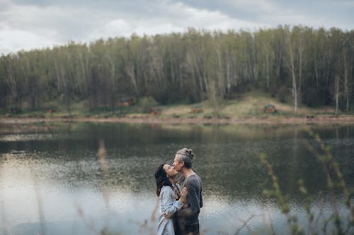 Free Couple standing close to each other near lake Stock Photo