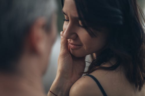 Crop anonymous man gently caressing face of girlfriend with closed eyes during romantic date