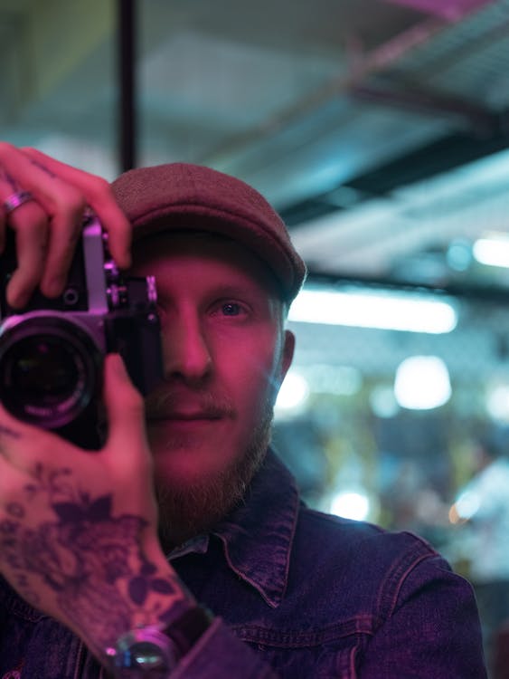 Man in Denim Jacket Holding Black Camera