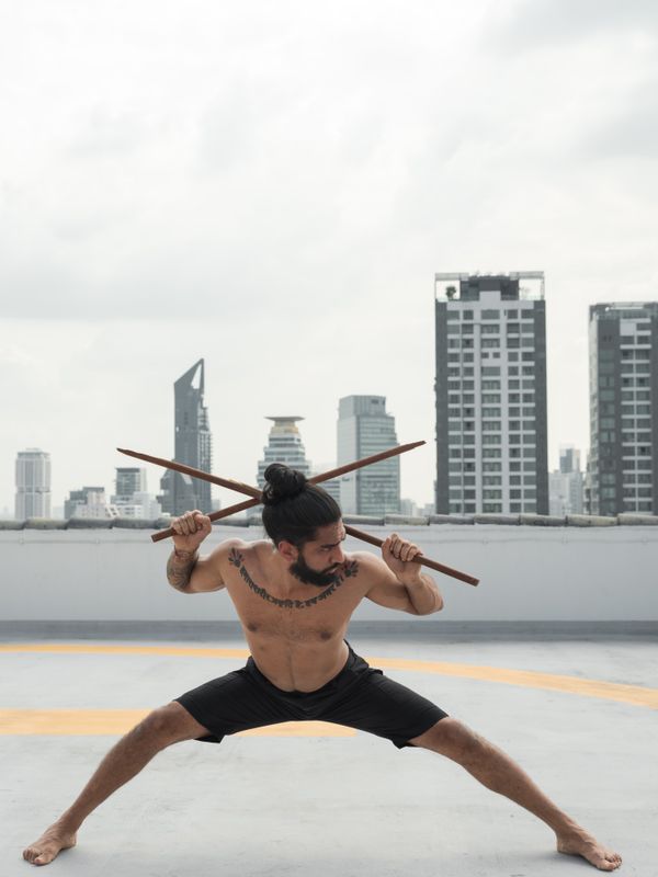 Martial artist training with two sticks on a city rooftop
