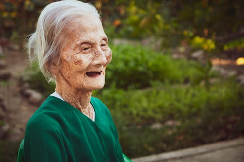 Senior woman with gray hair in green garden