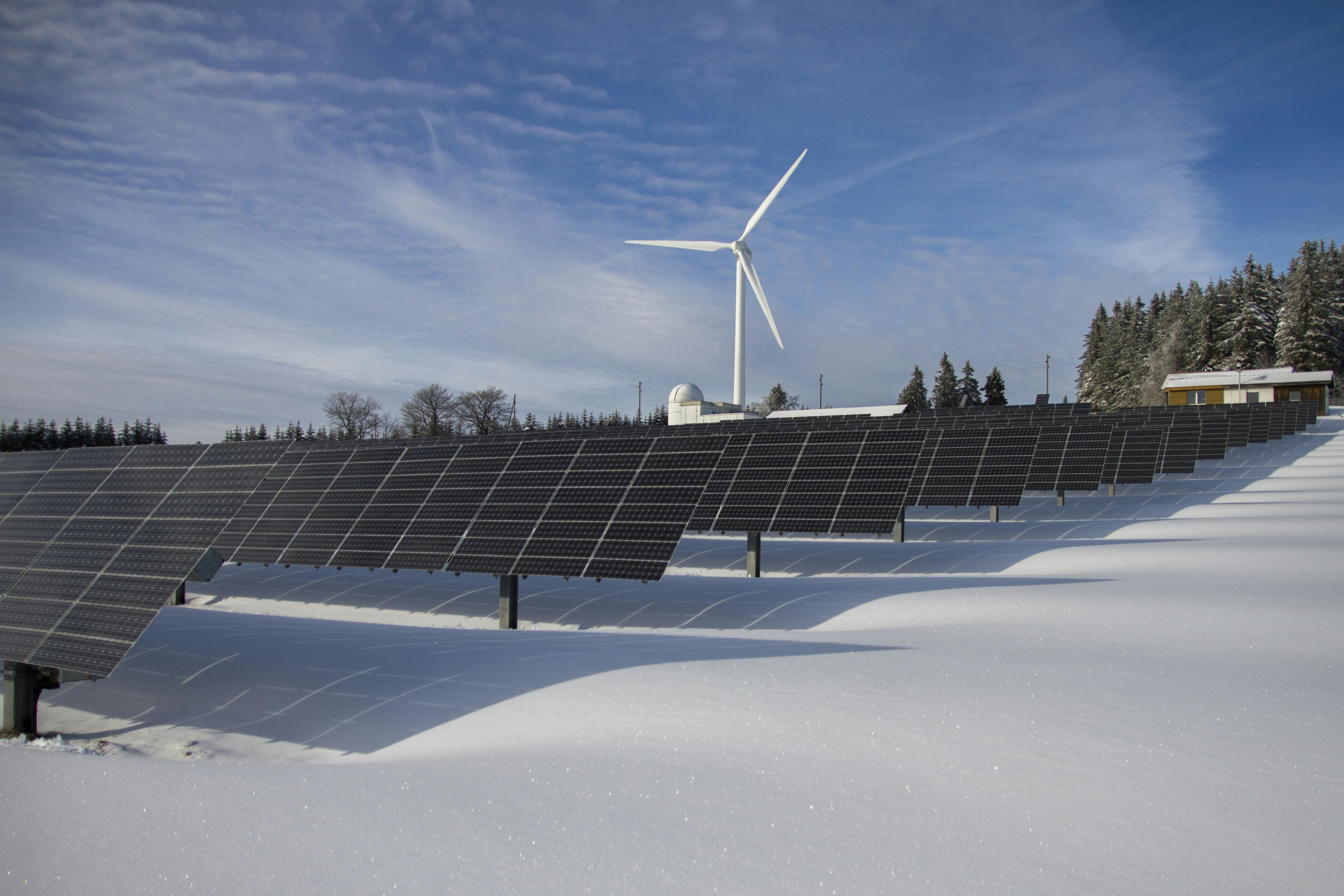 Solar panels and wind turbine in a snowy landscape