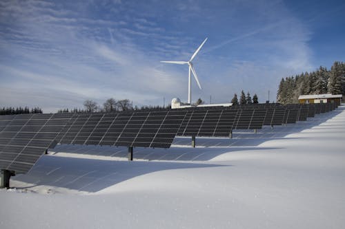 Painéis Solares Na Neve Com Moinho De Vento Sob Céu De Dia Claro