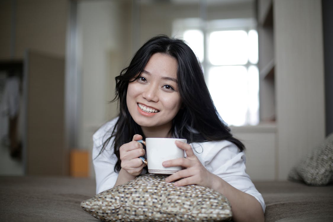 Cheerful Asian woman resting on bed in morning