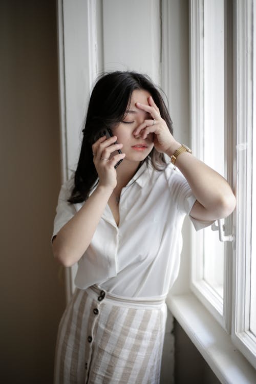 Photo of a Woman Talking on the Phone while Her Hand is on Her Face