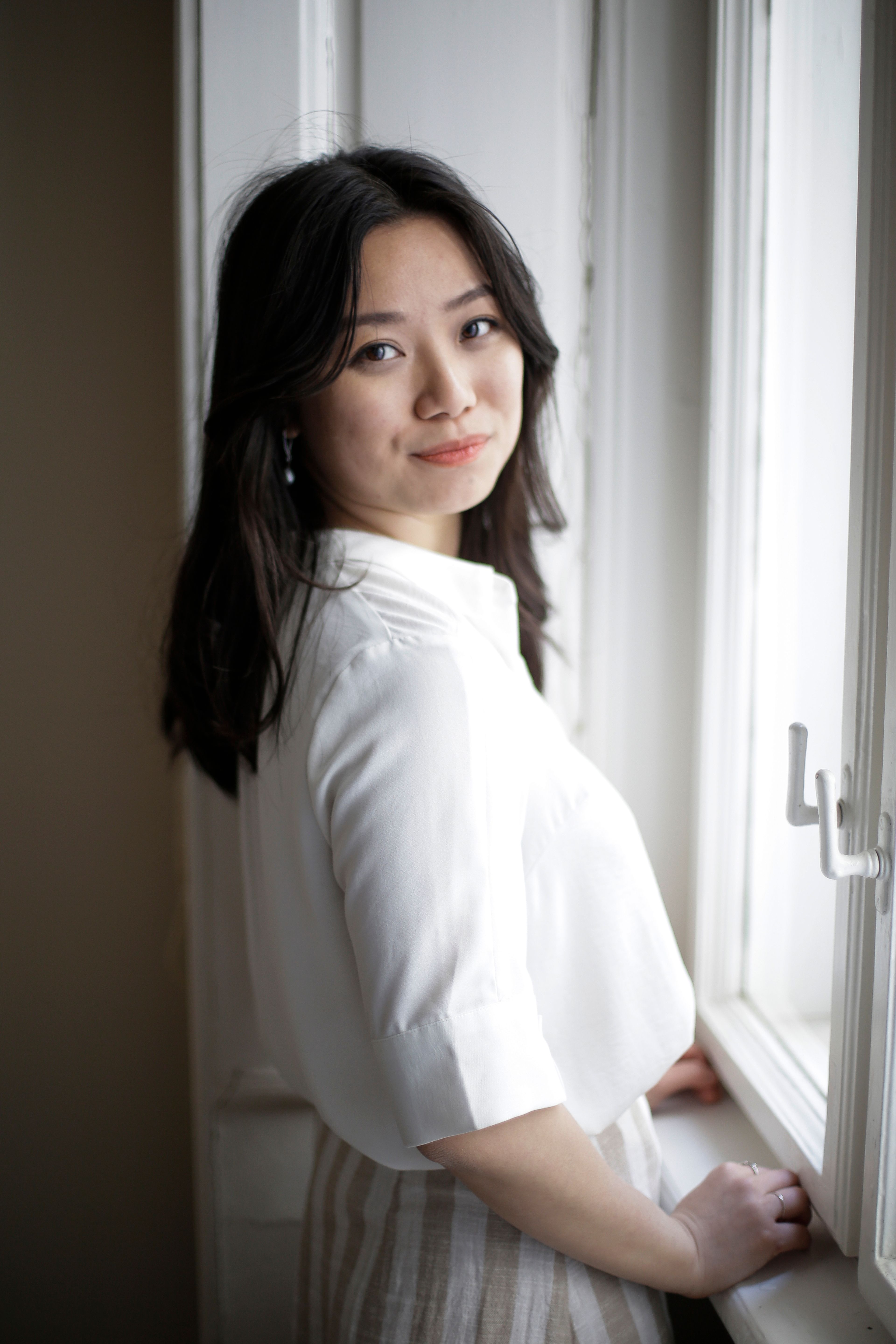 Positive Asian woman resting near window · Free Stock Photo