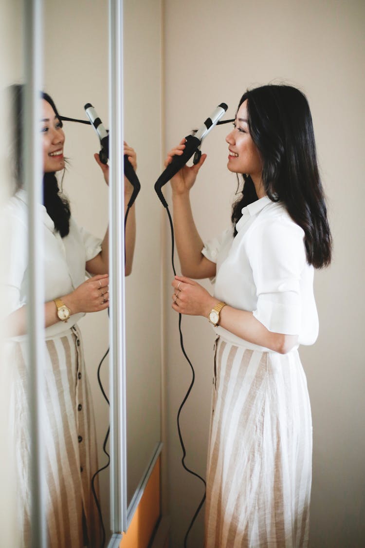 Cheerful Asian Woman Curling Hair