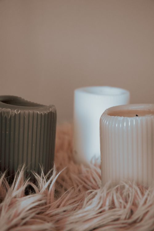 Free Warm-toned candles resting on a fluffy wool surface, ideal for cozy home decor. Stock Photo