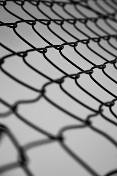 From below closeup chain link barrier of enclosure against gray sky on dull day
