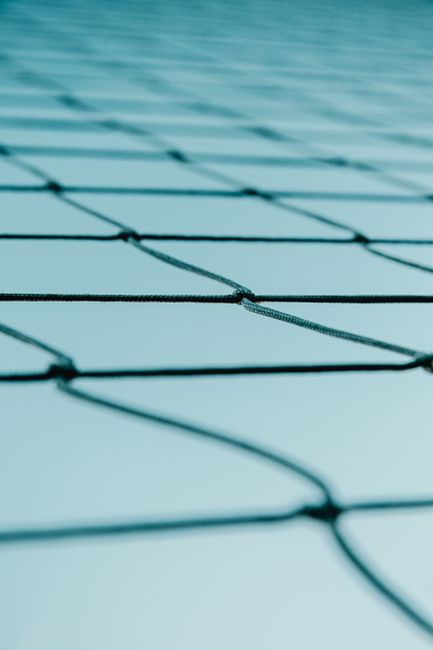 From below metal net barrier of property enclosure located against cloudless blue sky