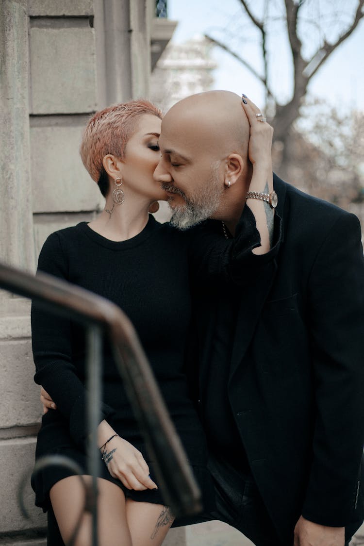 Stylish Adult Couple In Black Outfits Kissing On Street