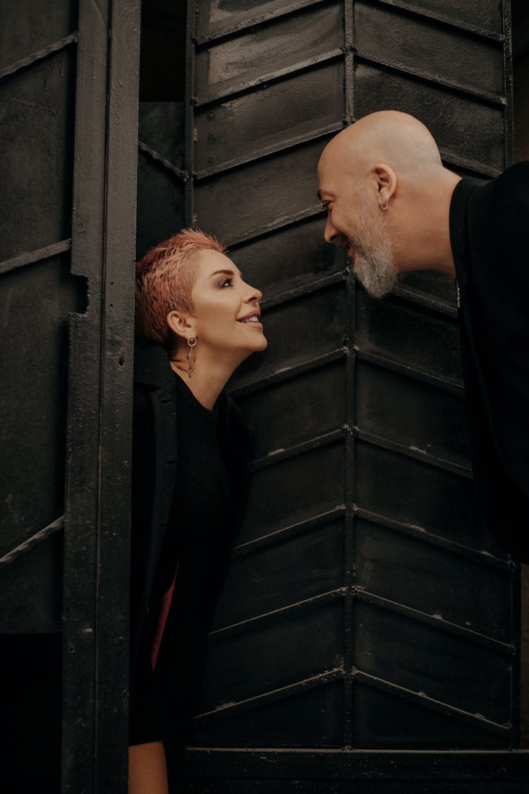 Flirty Mature Couple Standing At Metal Doorway