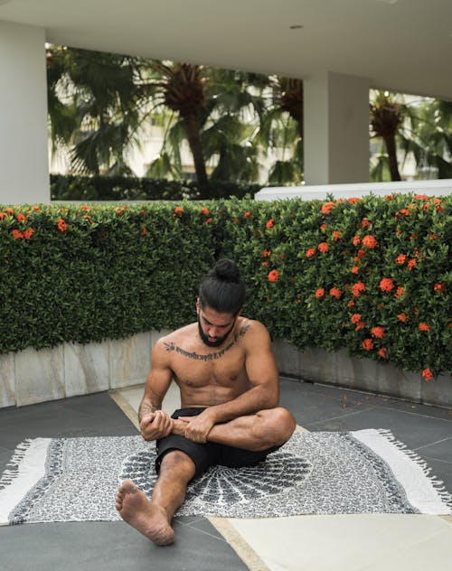 Photo of Man in Black Shorts Sitting While Stretching His Leg