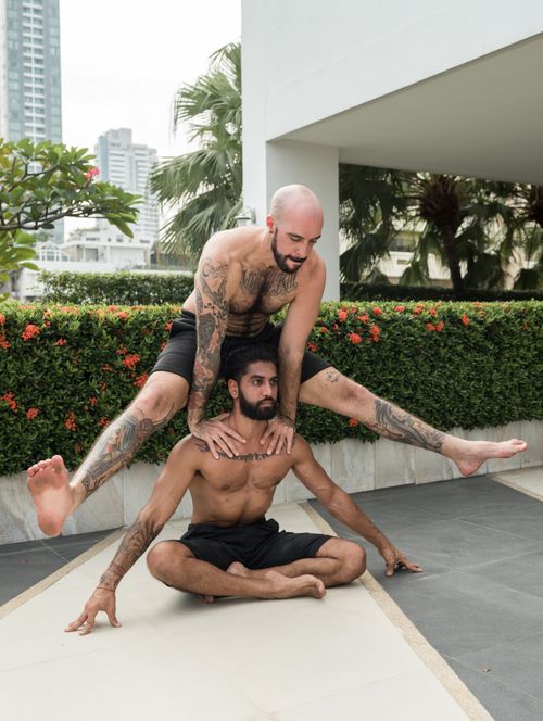 Free Two men perform a dynamic yoga acrobatic pose outdoors, showcasing balance and strength. Stock Photo