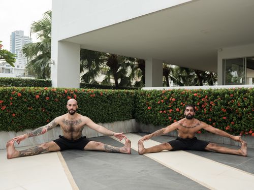 Free Two men engage in an outdoor yoga session, showcasing flexibility and concentration. Stock Photo