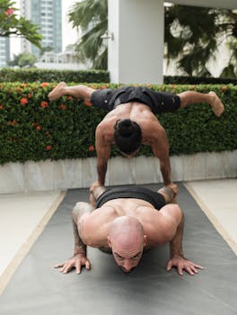 Two men engage in dynamic acro yoga showcasing strength and flexibility on a sunny urban terrace.