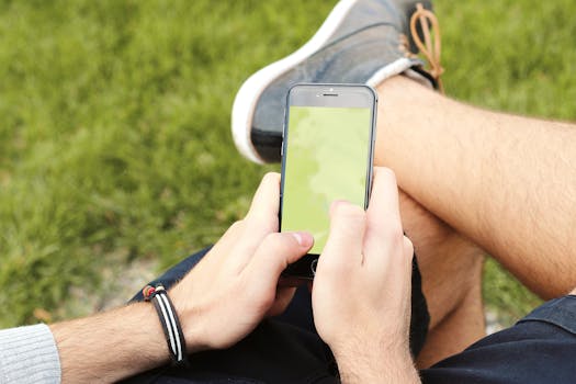 Person using smartphone outdoors with blank screen, providing mockup opportunity.