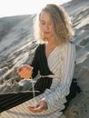 Stylish woman playing with sand on beach