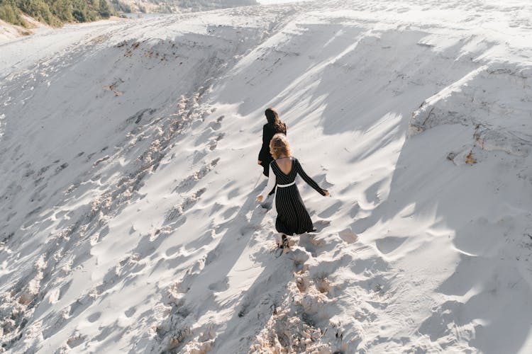 Unrecognizable Women Walking On White Sand Dune